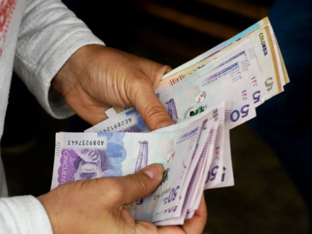 Una persona cuenta billetes colombianos