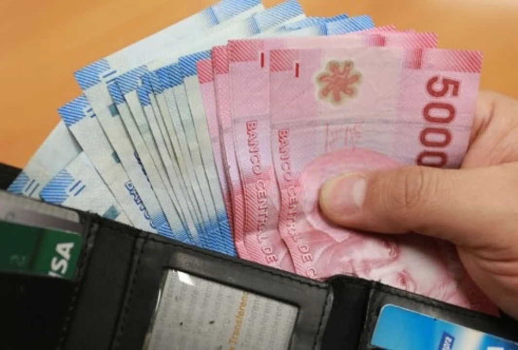 Una persona saca pesos chilenos de su billetera